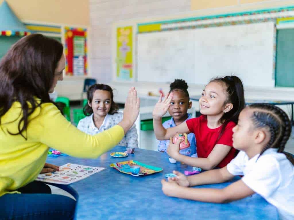 Proyecto de tesis en educación inicial: actividades lúdicas y trabajo en equipo en el aula Docente realizando actividad lúdica con grupo de niños en aula, promoviendo la participación y el trabajo en equipo durante una clase de educación inicial.