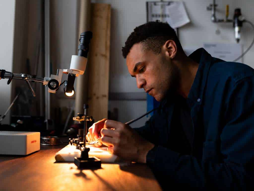 Ensayo de precisión en componente mecánico para tesis de grado en Ingeniería Mecánica Estudiante de Ingeniería Mecánica realizando ensayo de precisión en componente mecánico bajo microscopio en laboratorio de tesis de grado.