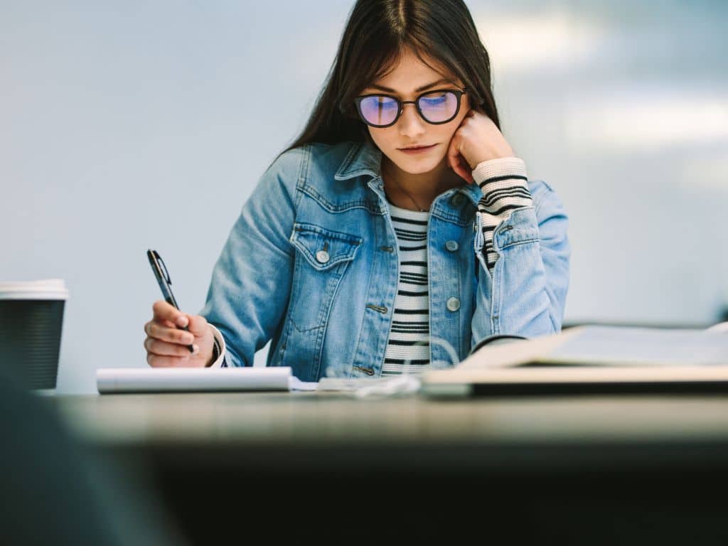 Análisis y mejoras en la revisión de tesis académica Joven tomando apuntes y reflexionando sobre observaciones para la revisión de su tesis académica